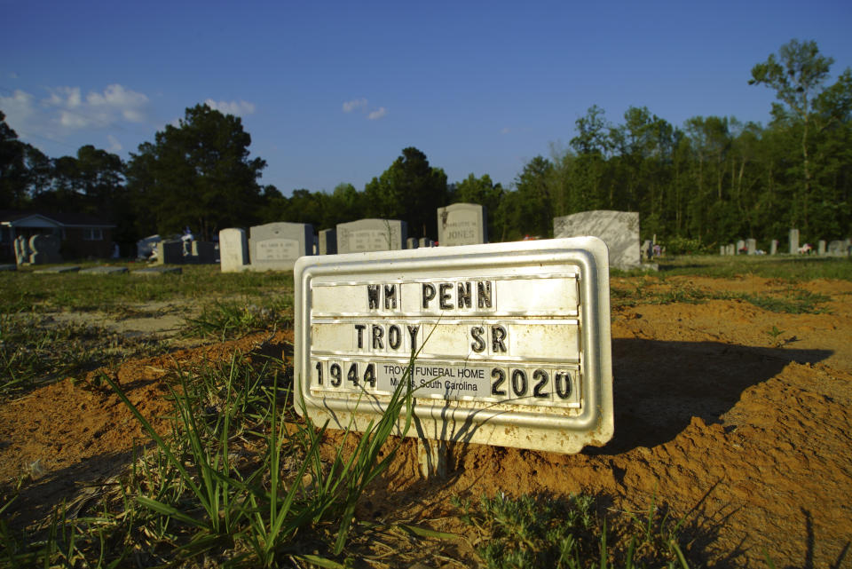 A tin plaque marks the grave of William Penn Troy Sr. at Hillcrest Cemetery outside Mullins, S.C., on Sunday, May 23, 2021. Troy died of COVID-19 in August 2020, one of many Black funeral home directors to succumb during the pandemic. (AP Photo/Allen G. Breed)