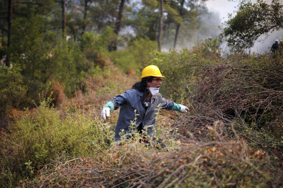 A Turkish volunteer tries to find a way through the bush as they fight wildfires in Turgut village, near tourist resort of Marmaris, Mugla, Turkey, Wednesday, Aug. 4, 2021. As Turkish fire crews pressed ahead Tuesday with their weeklong battle against blazes tearing through forests and villages on the country's southern coast, President Recep Tayyip Erdogan's government faced increased criticism over its apparent poor response and inadequate preparedness for large-scale wildfires.(AP Photo/Emre Tazegul)