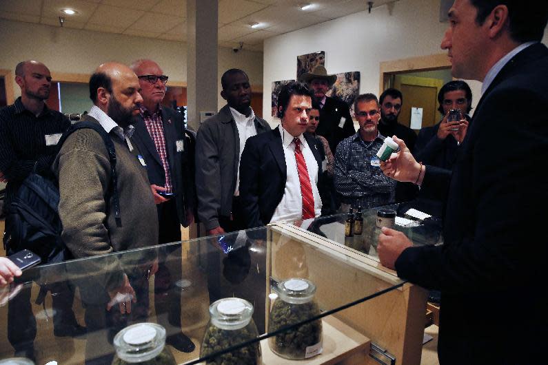 FILE - In this Oct. 23, 2013, Norton Arbelaez, right, the owner of River Rock marijuana dispensary, shows his products to foreign lawmakers, Julio Bango, of Uruguay, second from left, Larry Campbell, of Canada, third from left, and Fernando Belaunzaran, of Mexico, fifth from left, during a tour of his business in Denver. Several foreign lawmakers pushing for drug law reforms at home took a close up look the evolving legal marijuana industry in Colorado. Washington and Colorado passed recreational laws in 2012 to regulate the growth and sale of taxed pot at state-licensed stores. Sales began Jan. 1 in Colorado, and are due to start later this year in Washington. Twenty states and the District of Columbia also now have medical marijuana laws. (AP Photo/Brennan Linsley, File)