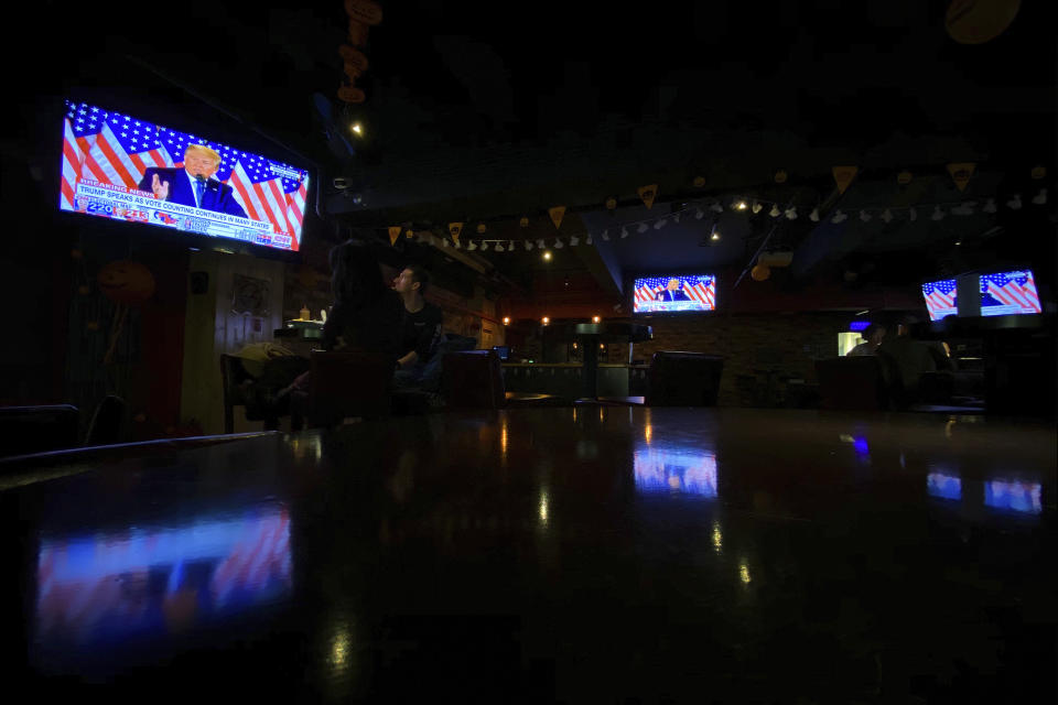 Customers watch TVs showing a live telecast of President Donald Trump speak in the East Room of the White House during the U.S. election, at a quiet pub in Beijing, Wednesday, Nov. 4, 2020. (AP Photo/Andy Wong)