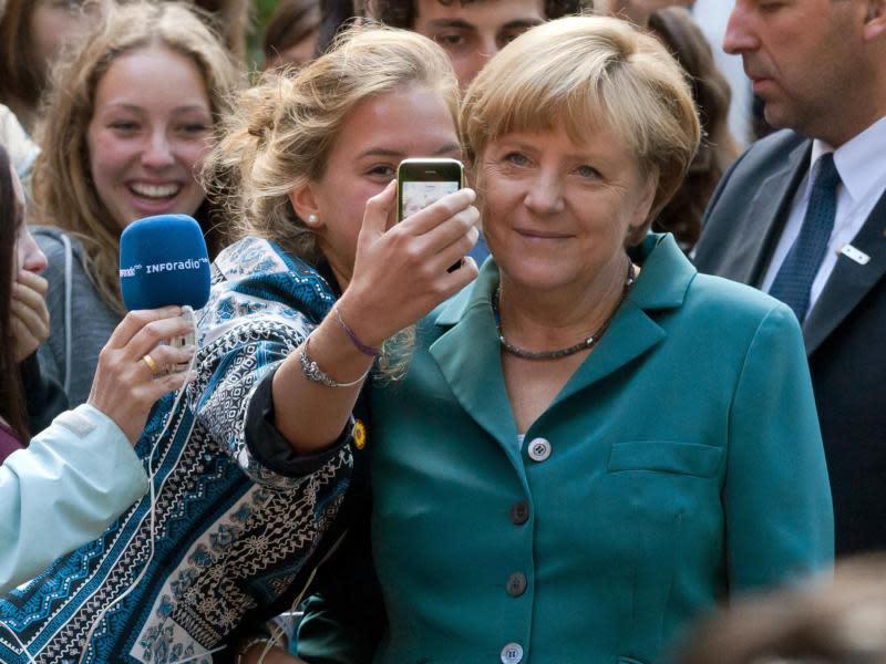 Angela Merkel lässt sich beim Besuch des Heinrich Schliemann Gymnasiums in Berlin mit einer Schülerin fotografieren. Foto: Tim Brakemeier