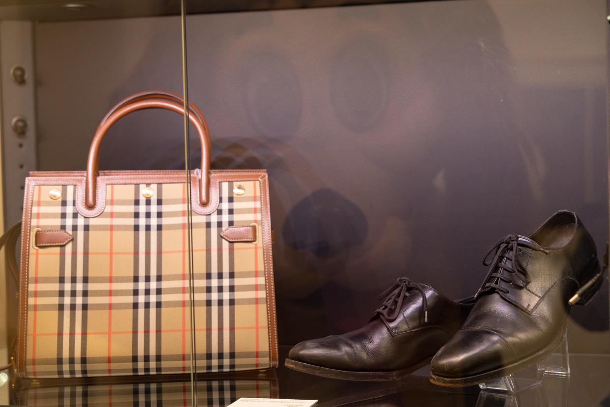 A brown striped handbag next to a pair of black dress shoes