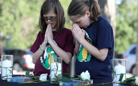 Two young girls pray during a vigil held at the Texas First Bank after the shooting at Santa Fe High School - Credit: Trish Badger/Reuters