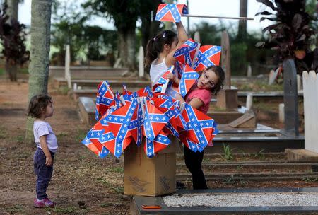 Descendants of American Southerners play with confederate flags in a cemetery where American Southern immigrants are buried during a party to celebrate the 150th anniversary of the end of the American Civil War in Santa Barbara D'Oeste, Brazil, April 25, 2015. REUTERS/Paulo Whitaker