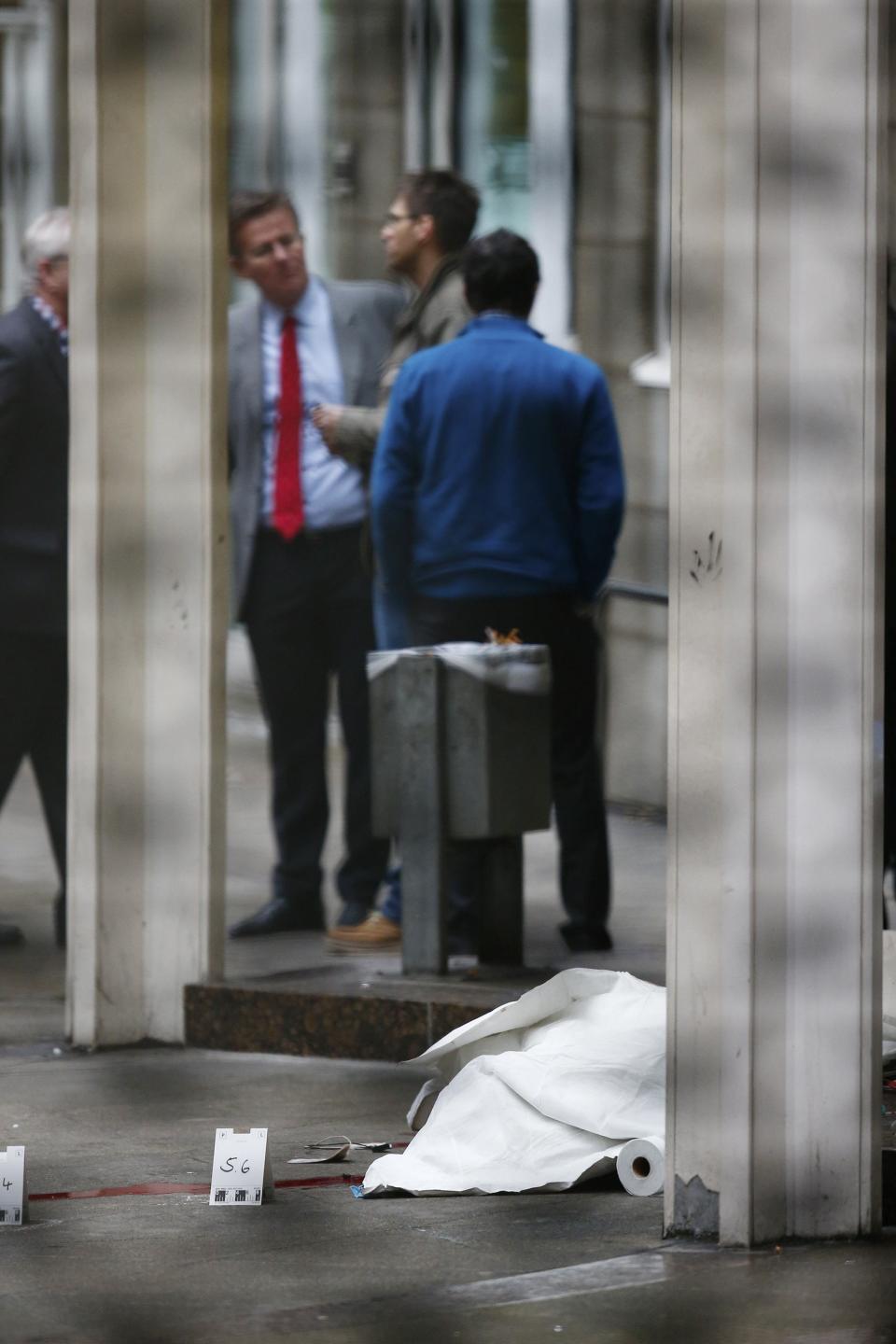 A covered body lies on the ground at the crime scene following a shooting at the entrance of Building E of the courthouse in Frankfurt January 24, 2014. REUTERS/Ralph Orlowski (GERMANY - Tags: CRIME LAW)