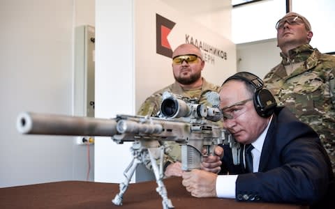 Russia's President Vladimir Putin (front) aims a rifle at the Kalashnikov shooting centre at Patriot military park. - Credit: Tass