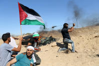 <p>A Palestinian protester uses a sling to hurl stones towards Israeli troops as others take cover during clashes near the border between Israel and Central Gaza Strip, May 26, 2017. (Photo: Ibraheem Abu Mustafa/Reuters) </p>