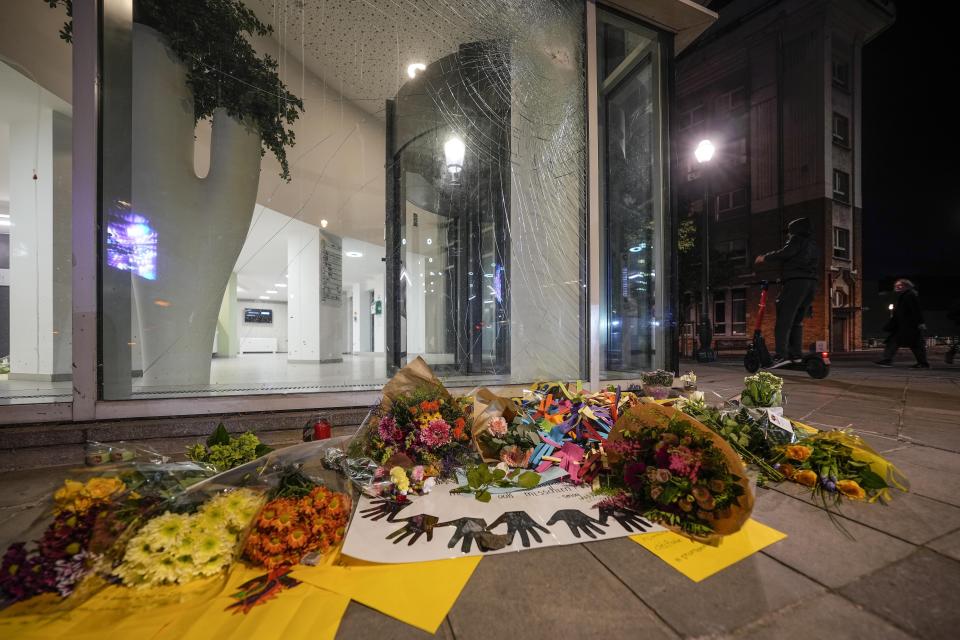 Flores yacen en el exterior de un edificio de oficinas en Bruselas, la noche del martes 17 de octubre de 2023, cerca del lugar donde dos aficionados del fútbol de Suecia fueron asesinados por un extremista tunecino la noche del lunes. (AP Foto/Martin Meissner)