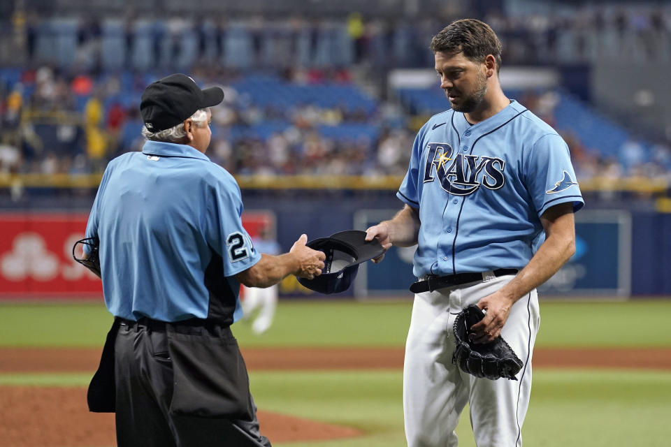 Home plate umpire Tom Hallion (20) checks Tampa Bay Rays starting pitcher Rich Hill's hat for any foreign substances as he leaves the game against the Boston Red Sox during the fifth inning of a baseball game Wednesday, June 23, 2021, in St. Petersburg, Fla. (AP Photo/Chris O'Meara)