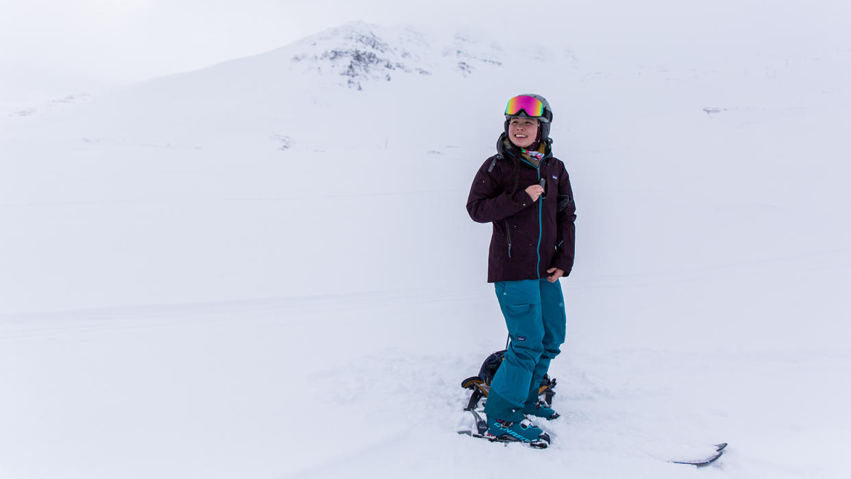  A woman wearing ski gear including a Patagonia Women’s Storm Shift Jacket stands on skis in snow. 