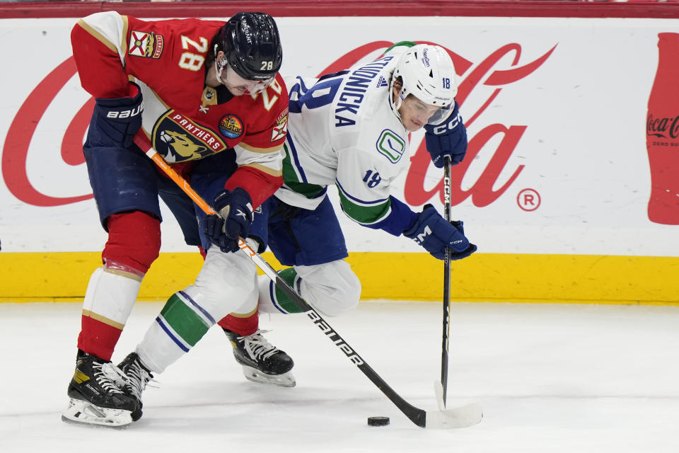 Florida Panthers defenseman Josh Mahura (28) and Vancouver Canucks center Jack Studnicka (18) battle for the puck during the second period of an NHL hockey game, Saturday, Jan. 14, 2023, in Sunrise, Fla. (AP Photo/Wilfredo Lee)