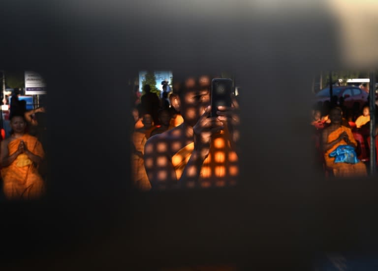 A Buddhist monk takes mobile photos of the police blockade through the closed gate of the Dhammakaya temple, north of Bangkok, on February 16, 2017