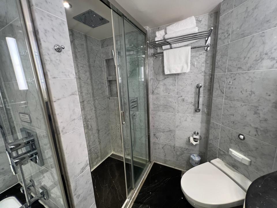 toilet with marble walls and shower area