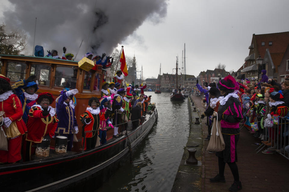 In this Saturday Nov. 16, 2013, file image, people react to the arrival of Black Petes, the blackface sidekicks of Sinterklaas, the Dutch version of Santa Claus, in the harbor of Hoorn, Netherlands. The death of George Floyd at the hands of Minneapolis police officers has sparked a reexamination of many countries' colonial histories, actions and traditions, that often were exalted in the form of statues and other memorials. The Netherlands has been wrestling for years with issues of racism, with much of the debate revolving around the divisive children's character Black Pete, who is usually portrayed by white people wearing blackface makeup at celebrations each December marking Sinterklaas, a Dutch celebration of St. Nicholas. (AP Photo/Peter Dejong, File)