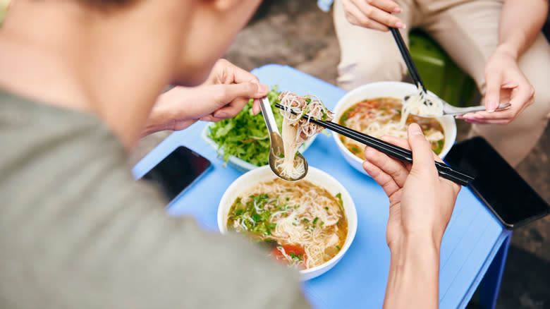 Couple eating phở in Hanoi