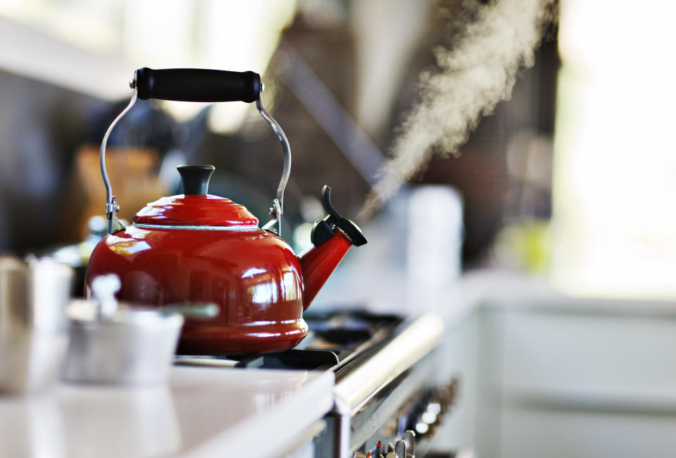 Red old fashion kettle on cooker with steam coming out