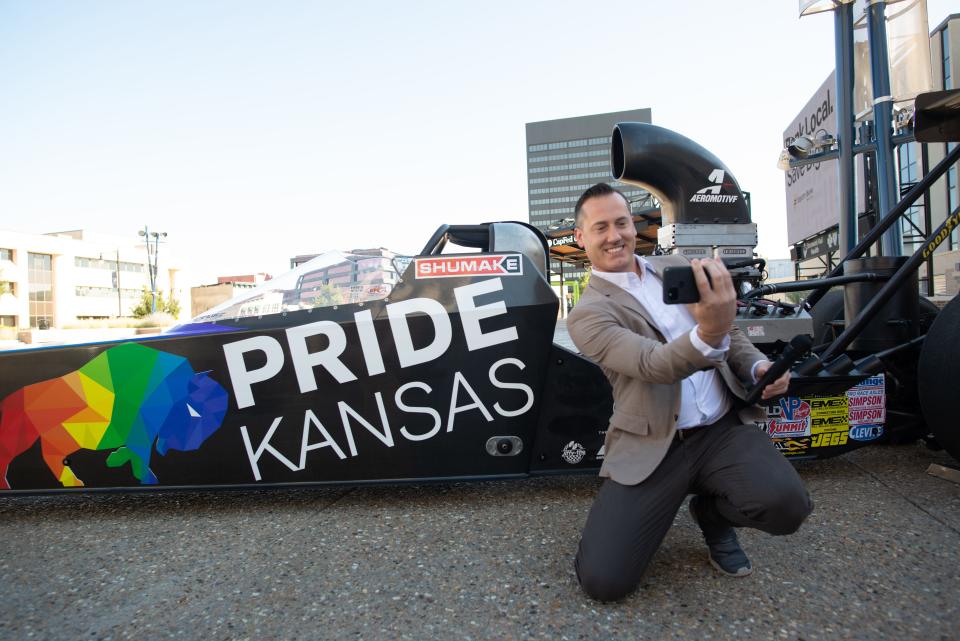 Sean Dixon, president of Visit Topeka, takes a selfie with Travis Shumake's drag car during a media event at Evergy Plaza Wednesday.