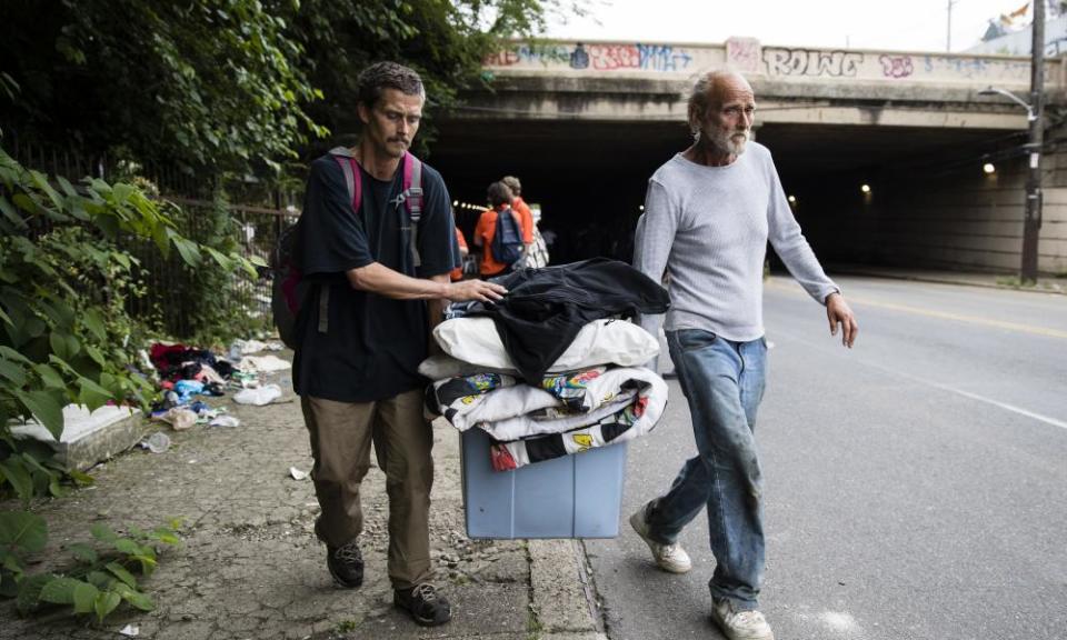 Jason Carmine, left, and his father Kevin Carmine, who say they both are addicted to heroin, carry their belongings from an encampment on Wednesday.