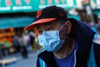 A man wears a face mask while waiting for a public bus in the Chinatown section of San Francisco