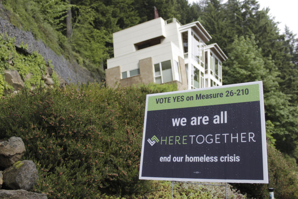 A campaign sign urging people to vote "Yes" on Measure 26-210, which would approve taxes on personal income and business profits to raise $2.5 billion over a decade to fight homelessness, is displayed near an upscale home, Thursday, May 14, 2020, in Portland, Ore. Voters in metropolitan Portland will vote on the measure Tuesday, May 19, and the result of the ballot question amid the coronavirus pandemic will be instructive for other West Coast cities that are struggling to address burgeoning homeless populations as other revenue streams dry up. (AP Photo/Gillian Flaccus)