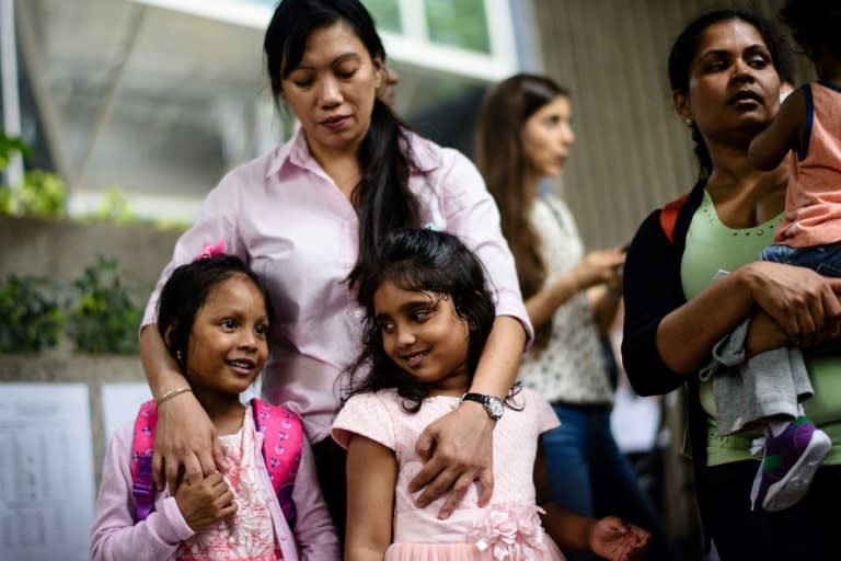 Sri Lankan refugee Nadeeka (R) holds her baby boy Danath as her daughter Sethumdi (front C) stands with Keana (front L), daughter of Filipino refugee Vanessa Rodel (back C), as they meet the press outside the Immigration Tower in Hong Kong