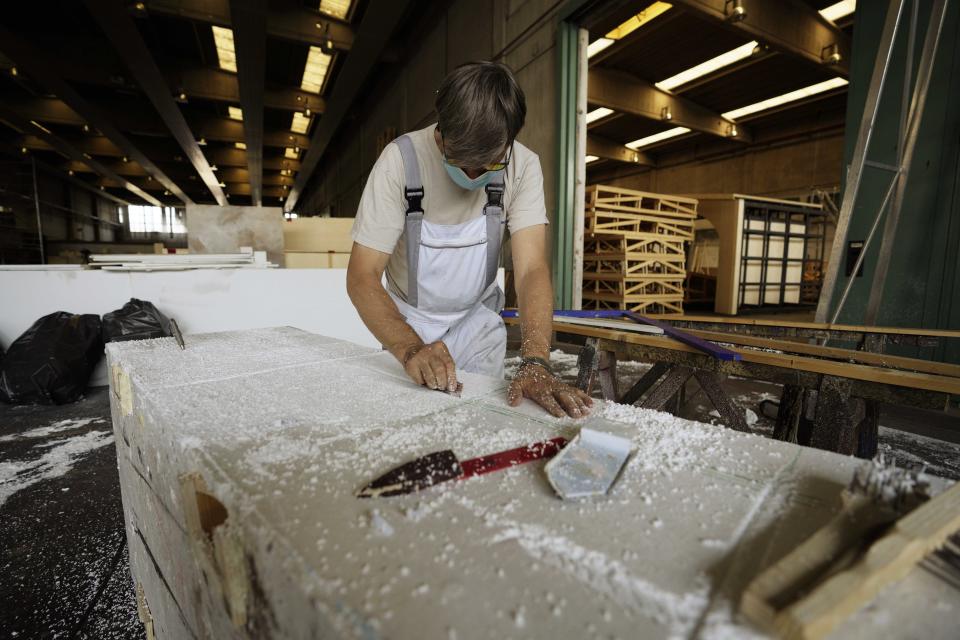 An artisan works on a backdrop at the scenery lab of the Arena di Verona theatre, in Verona, Italy, Friday, June 25, 2021. The Verona Arena amphitheater returns to staging full operas for the first time since the pandemic struck but with one big difference. Gone are the monumental sets that project the scene to even nosebleed seats in the Roman-era amphitheater, replaced by huge LED screens with dynamic, 3D sets that are bringing new technological experiences to the opera world.(AP Photo/Luca Bruno)