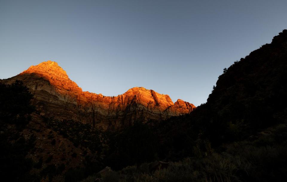 Cliffs glow orange as the sun sets on The Watchman