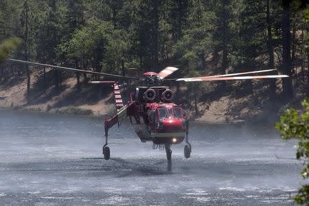 A firefighting helicopter fills up with water from Jenks Lake as firefighters battle the Lake Fire in the San Bernardino National Forest, California June 19, 2015. REUTERS/David McNew