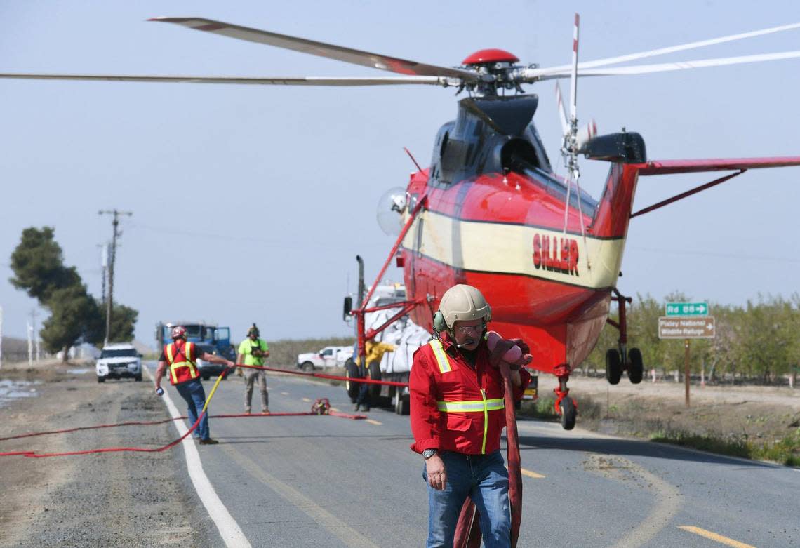 Dushan “Duke” Puharich, senior safety officer with Siller Helicopters Incorporated, walks away as a helicopter prepares to lift a large bag of sand, gravel and aggregate to drop on the levee break along Deer Creek Saturday afternoon, March 18, 2023.