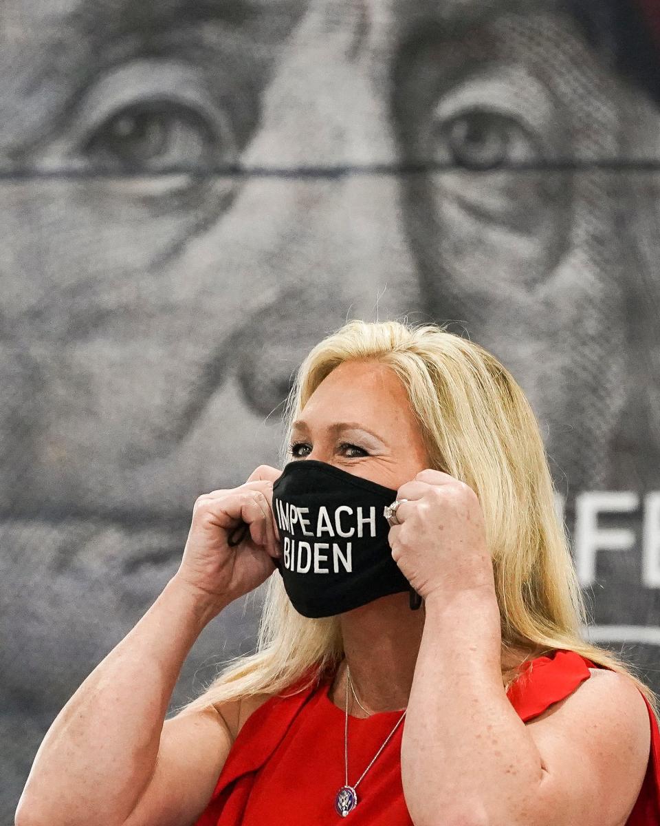 U.S. Rep. Marjorie Taylor Greene holds a "Impeach Biden" mask to her face before speaking to a crowd of about 400 people gathered at the Indian River County Fairgrounds for the "America First Rally" Saturday, April 24, 2021, in Indian River County. The event was hosted by the Republican Woman of Indian River.