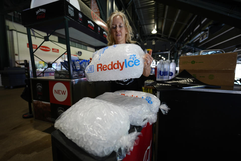 Cheryl Batch picks up a bag of ice to use to cool beverages at a stand on the main concourse of Coors Field before the Colorado Rockies host the Pittsburgh Pirates in a baseball game Sunday, June 16, 2024, in Denver. (AP Photo/David Zalubowski)