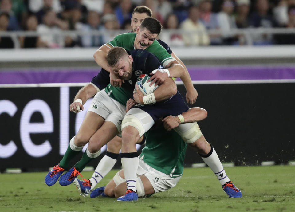 Scotland's John Barclay, centre, is tackled by Ireland's Josh van der Flier and Jonathan Sexton, left, during the Rugby World Cup Pool A game at International Stadium between Ireland and Scotland in Yokohama, Japan, Sunday, Sept. 22, 2019. (AP Photo/Jae Hong)