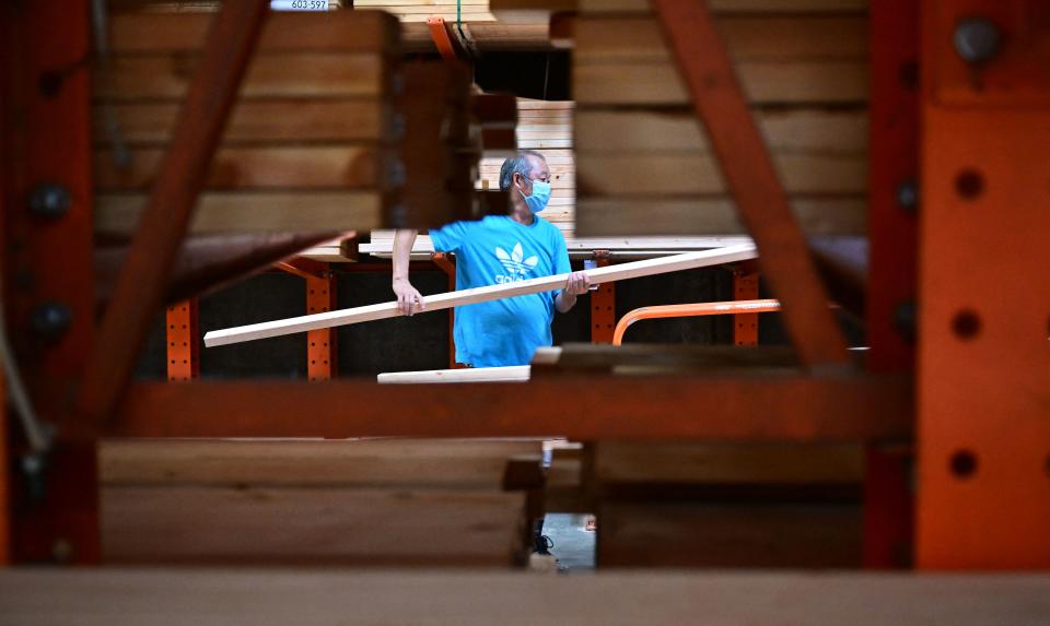 A man loads pieces of two-by-four wood onto his cart in the lumber section at a home improvement store on August 16, 2022 in Alhambra, California. - Lumber prices have fallen as the US housing market shows continued signs of cooling amid high interest rates. (Photo by Frederic J. BROWN / AFP) (Photo by FREDERIC J. BROWN/AFP via Getty Images)