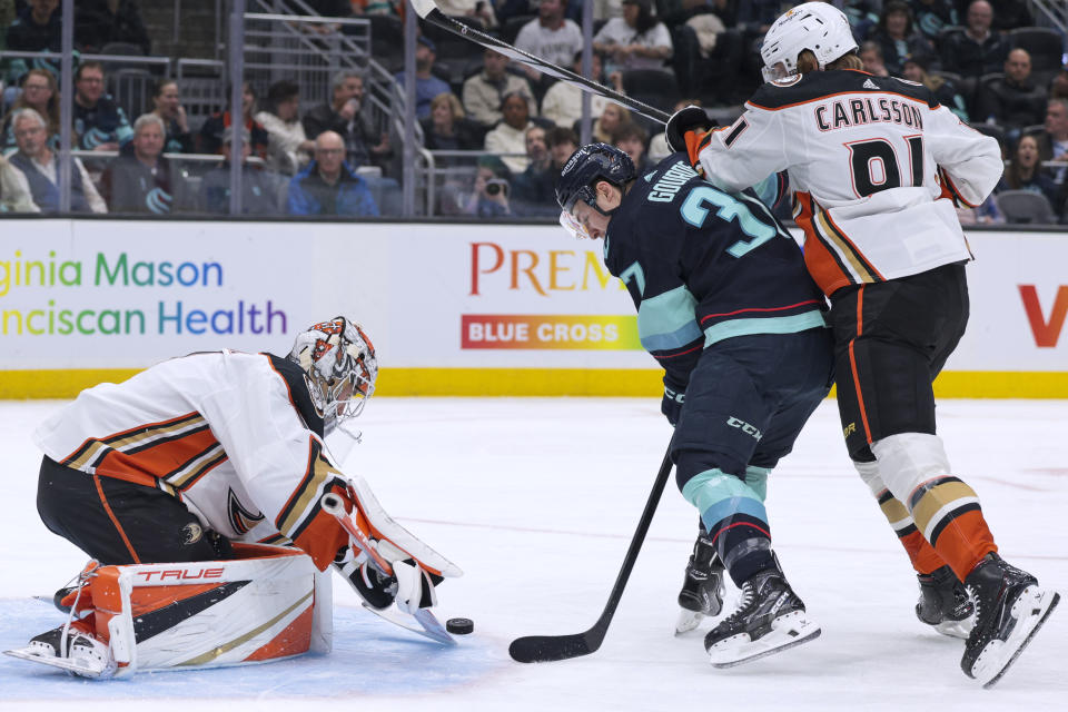 Seattle Kraken center Yanni Gourde (37) tries to score as Anaheim Ducks goaltender Lukas Dostal (1) goes for the puck and center Leo Carlsson (91) defends during the first period of an NHL hockey game Thursday, March 28, 2024, in Seattle. (AP Photo/Jason Redmond)