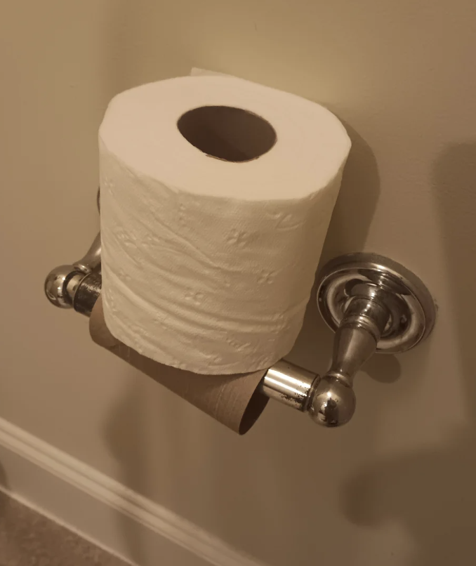 Toilet paper roll on a metal holder against a wall