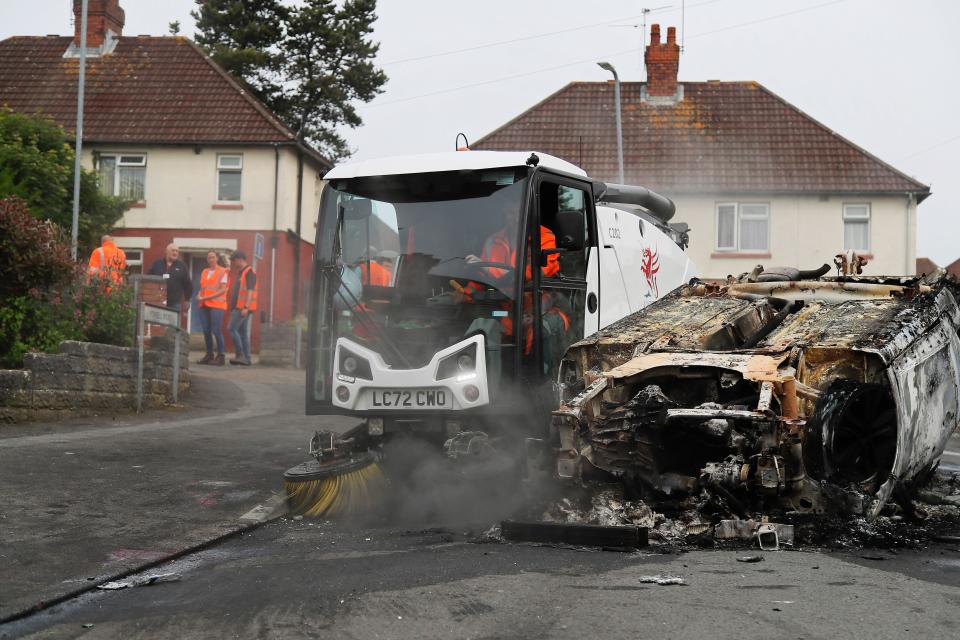 Council workers clear debris from the area immediately around a car that was set alight in Ely, Cardiff, following the riot that broke out after two teenagers died in a crash. Tensions reached breaking point after officers were called to the collision, in Snowden Road, Ely, at about 6pm on Monday. Officers faced what they called 