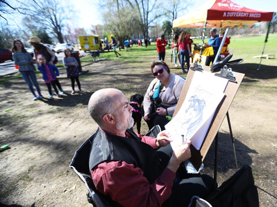 Hollywood Feed and Overton Park conservancy host Mardi Growl event for dog owners to bring their pets in costumes and compete in the costume contest on Mar. 4, 2023 at Overton Bark Park in Memphis. Tenn. An artist draws dogs during the Mardi Growl event.