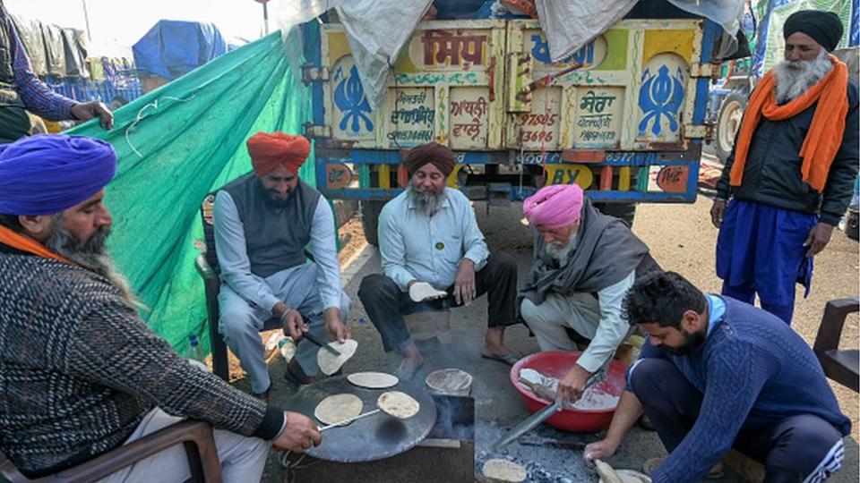 Farmers cook chapati breads beside a trolley near the Punjab-Haryana state border in Shambhu on February 16, 2024