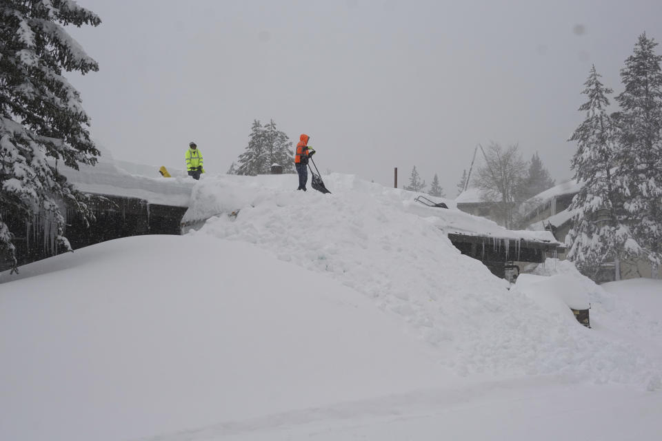 Workers clear snow off a roof during a blizzard Sunday, March 3, 2024, in Olympic Valley, Calif. (AP Photo/Brooke Hess-Homeier)