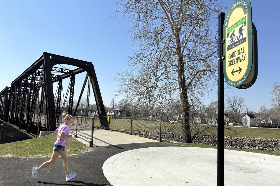 A woman runs by the Cardinal Greenway in Muncie, Ind. Wednesday, March 13, 2024. The Cardinal Greenways pathway born from eastern Indiana's abandoned railroad tracks will become a central cog in the Great American Rail Trail — a planned 3,700-mile network of uninterrupted trails spanning from Washington state to Washington, D.C. (AP Photo/Isabella Volmert)