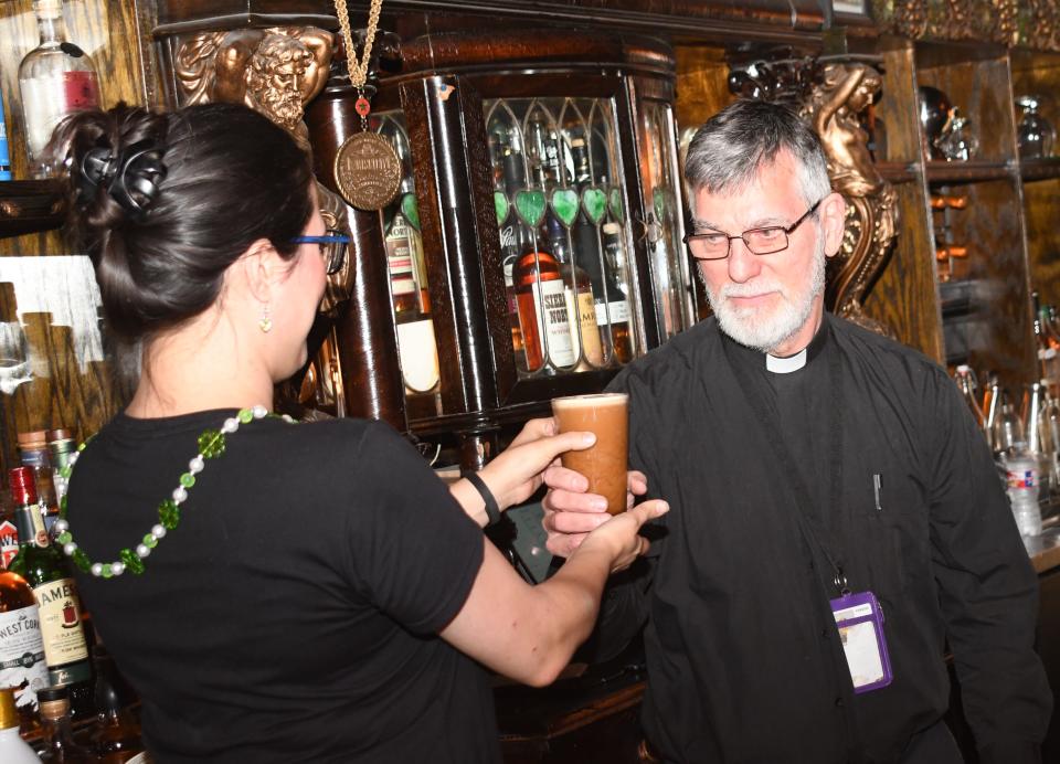 Melissa Scarborough (left), whisk(e)y sommelier and The Tasting Room of Louisiana owner, hands Father Stephen Brandow a glass of beer at the Blessing of the Beer held on St. Patrick's Day. No alcohol was served before the blessing and until Brandow drank the first glass.