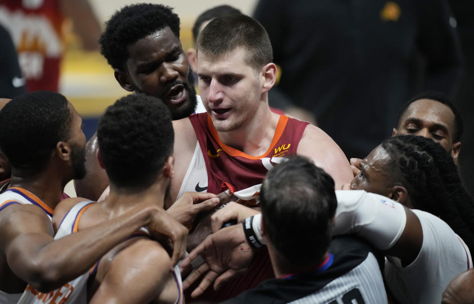 Denver Nuggets center Nikola Jokic, center, is restrained from fighting with Phoenix Suns guard Devin Booker, second from left in front, in the second half of Game 4 of an NBA second-round playoff series Sunday, June 13, 2021, in Denver. (AP Photo/David Zalubowski)