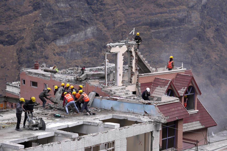 Laborers demolish a building which has developed cracks in Joshimath, in India's Himalayan mountain state of Uttarakhand, Jan. 19, 2023. Big, deep cracks had emerged in over 860 homes in Joshimath, where they snaked through floors, ceilings and walls, making them unlivable. Roads were split with crevices and multi-storied hotels slumped to one side. Authorities declared it a disaster zone and came in on bulldozers, razing down whole parts of a town that had become lopsided. (AP Photo/Rajesh Kumar Singh)