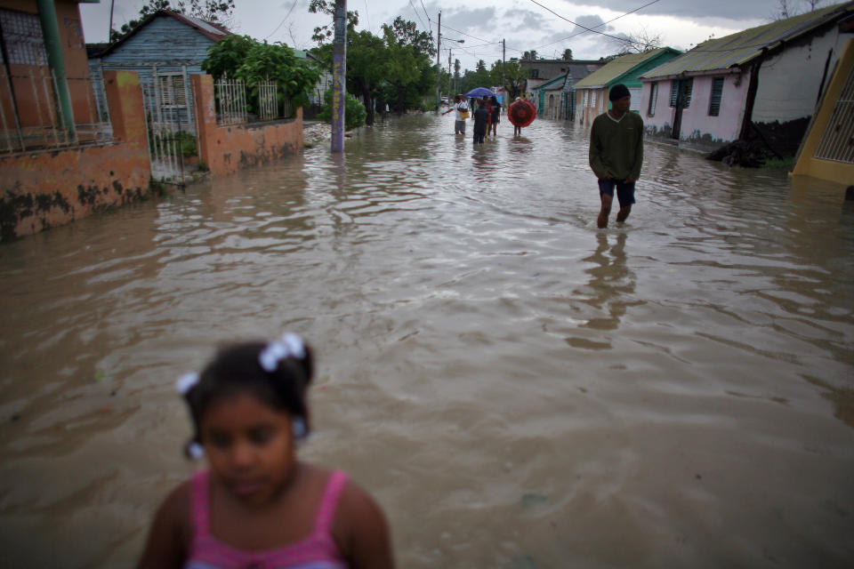 People walk thru flooded streets after Tropical Storm Isaac hit in Barahona, Dominican Republic, Saturday, Aug. 25, 2012. Forecasters said Isaac could dump as much as eight to 12 inches (30 centimeters) and even up to 20 inches (51 centimeters) on Hispaniola, which is shared by Haiti and the Dominican Republic, as well as produce a storm surge of up to 3 feet (0.9 meters). (AP Photo/Ricardo Arduengo)