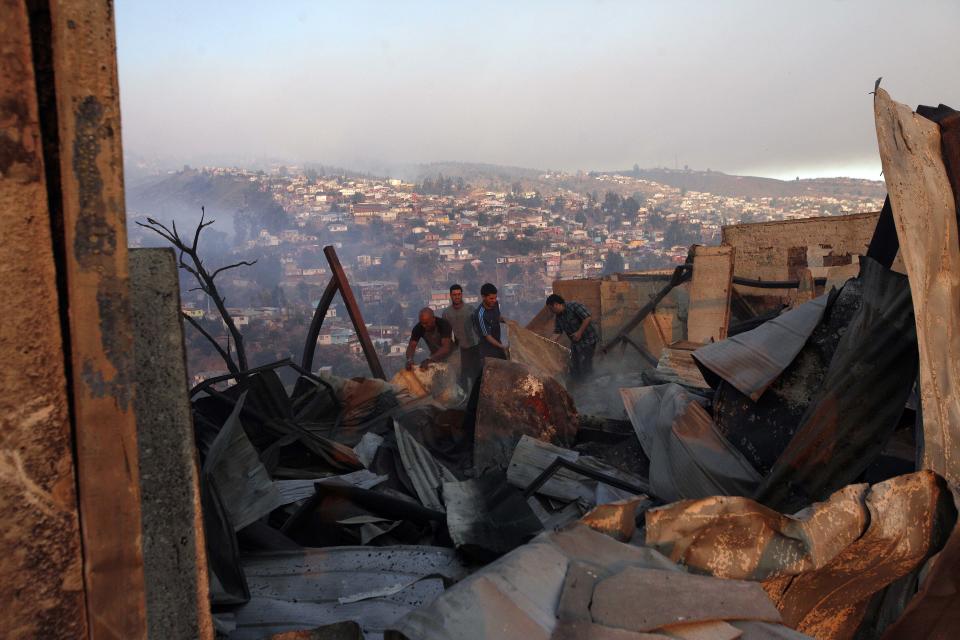 A group of people try to save items after a large forest fire reached urban areas in Valparaiso, Chile, Sunday April 13, 2014. Authorities say the fires have destroyed hundreds of homes, forced the evacuation of thousands and claimed the lives of at least seven people. ( AP Photo/ Luis Hidalgo)