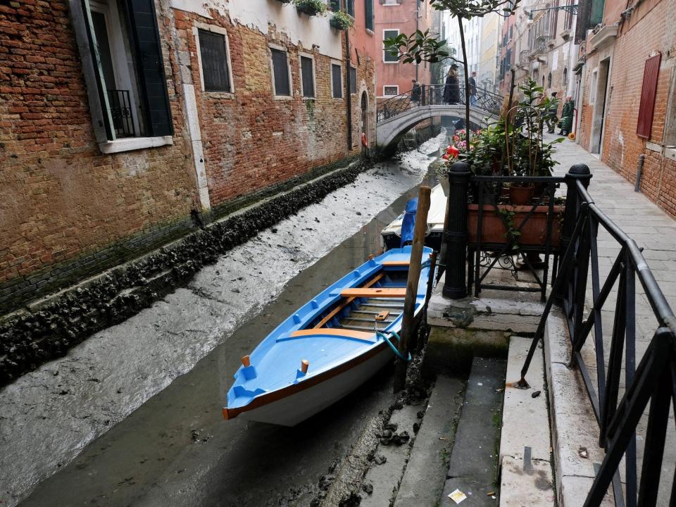 A gondola in a canal during a severe low tide in the lagoon city of Venice, resting almost on the bottom. February 17, 2023