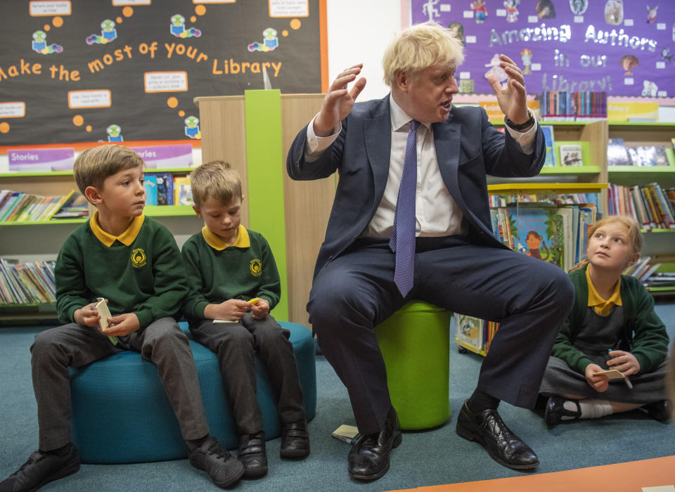 Britain's Prime Minister Boris Johnson, right, reacts with pupils during a visit to Middleton Primary School in Milton Keynes, England, Friday Oct. 25, 2019. European Union ambassadors agreed Friday that the bloc should grant Britain’s request for another extension to the Brexit deadline but have not yet figured out how long that delay should be. (Paul Grover/Pool via AP)