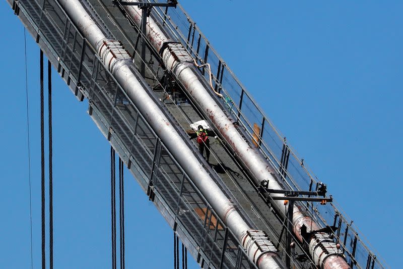 A construction worker scales the northeast cables of the George Washington Bridge duering reconstruction in New York