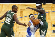 Orlando Magic guard Gary Harris, center, works to get between Milwaukee Bucks forward Khris Middleton (22) and guard Jrue Holiday during the first half of an NBA basketball game, Sunday, April 11, 2021, in Orlando, Fla. (AP Photo/John Raoux)