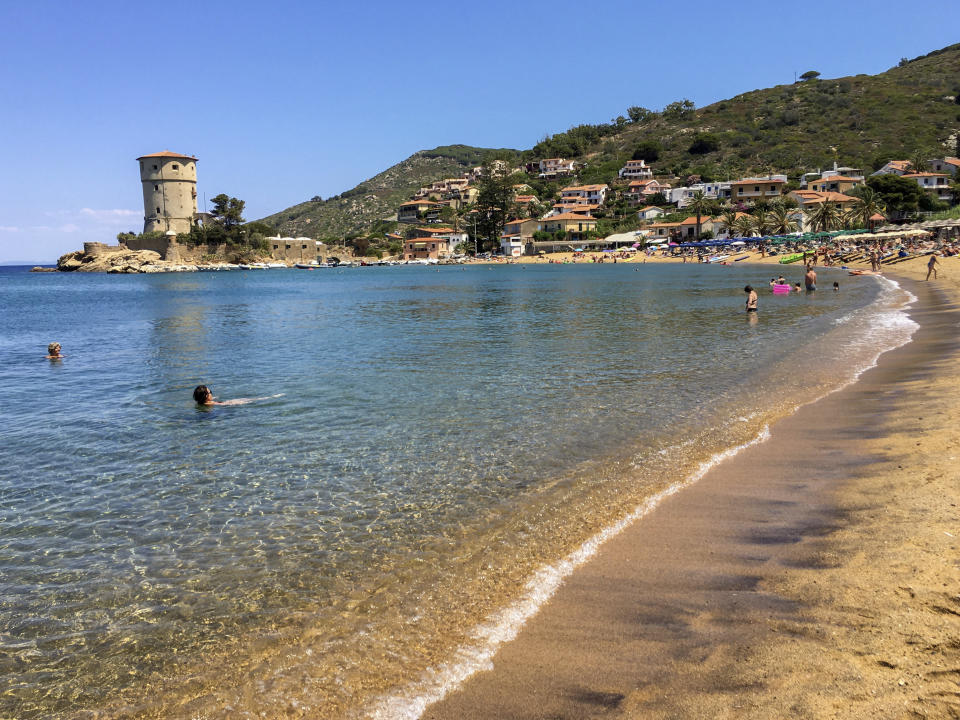 People enjoy the sun and the fresh water on a beach at the Giglio island, in front of Tuscany, Italy, Wednesday, June 24, 2020. In spite of various people with coronavirus stopped by the island at times, no one of the islanders developed COVID-19 infection. (AP Photo/Paolo Santalucia)